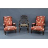 A pair of Edwardian mahogany armchairs, with floral upholstery, raised on ring turned supports,