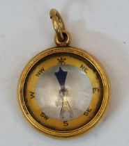 A gold fob compass, late 19th century, stamped 18ct, with suspension loop, 2.6cm diameter, gross