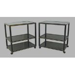 Pierre Vandel, Paris, a pair of black metal three tier side tables, raised on castors, 66cm high,