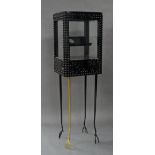 A contemporary display cabinet, the glazed black metal top with stud like mounts, raised on tapering