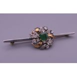 An unmarked gold diamond and emerald bar brooch. 5.5 cm long. 7 grammes total weight.