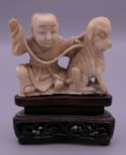 A 19th century Chinese carved ivory model of a boy and dog, mounted on a pierced wooden stand. 7.