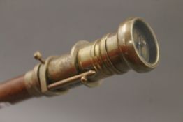 A walking stick topped with a telescope and compass. 97.5 cm long.