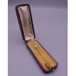 A pearl set unmarked gold stick pin, housed in a J. Chaumet box. 6 cm long.