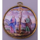 An antique Limoges enamel pendant depicting the crucifixion of Christ. 5 cm wide.