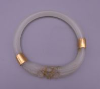 A Chinese gold mounted jade bangle carved with dragon heads. 8.5 cm exterior diameter and 6.