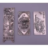 Three Chinese white metal scroll weights. The largest 14.5 cm long.