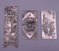 Three Chinese white metal scroll weights. The largest 14.5 cm long.