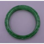 A carved jade bangle. 7.5 cm exterior diameter, 6 cm interior diameter.
