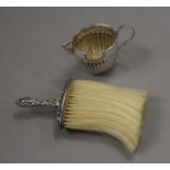 A small silver cream jug (53 grammes) and a silver handled crumb brush. The former 6.5 cm high.