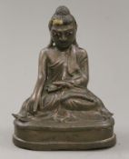 A bronze model of buddha with glass inset eyes. 16 cm high.