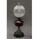 A Victorian oil lamp with red glass reservoir. 51 cm high.