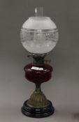 A Victorian oil lamp with red glass reservoir. 51 cm high.