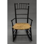 An Arts and Crafts rush seated ebonised rocking chair. 49.5 cm wide.