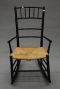 An Arts and Crafts rush seated ebonised rocking chair. 49.5 cm wide.