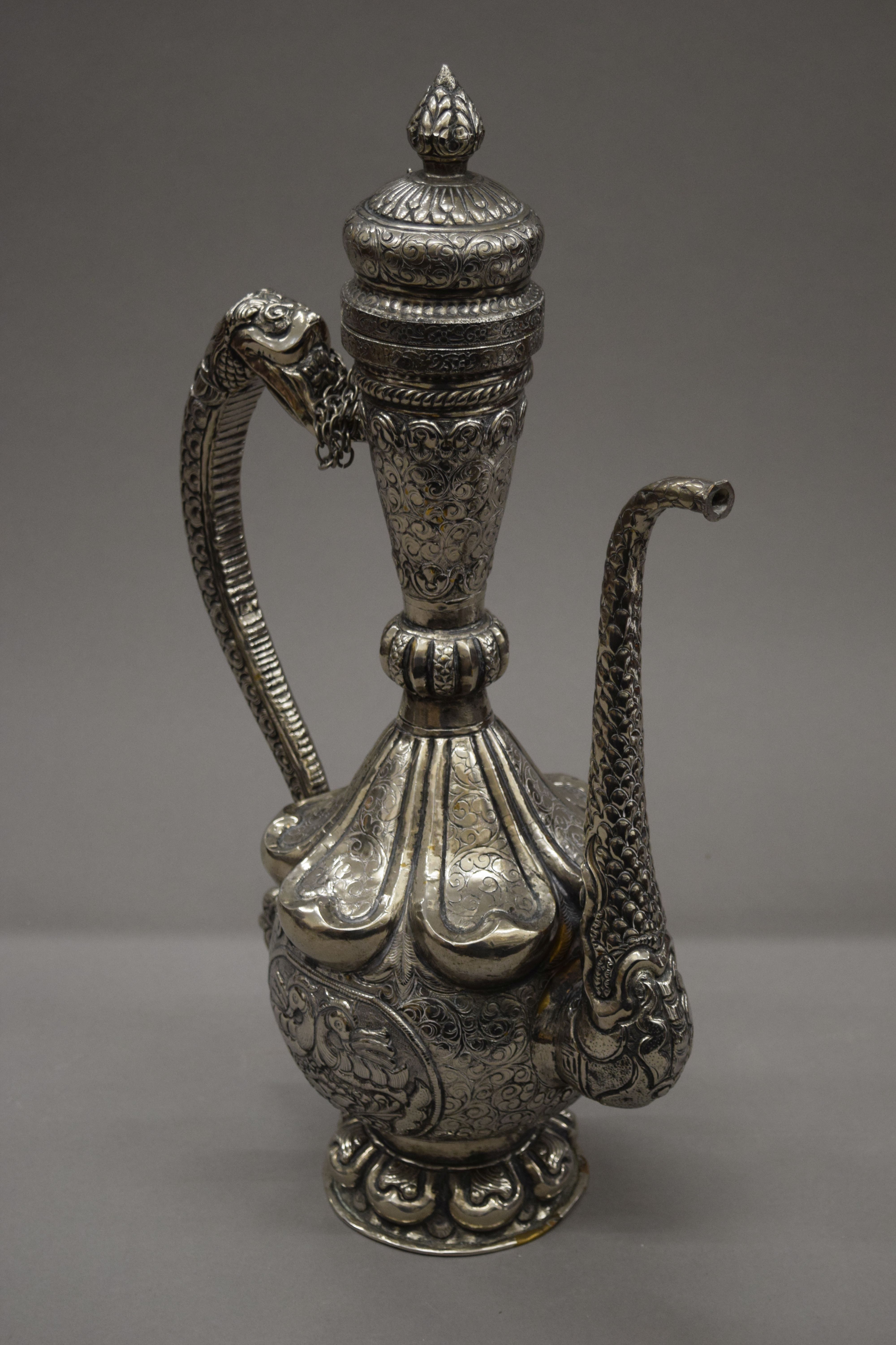 A Tibetan silver on copper repousse decorated ewer. 49 cm high.