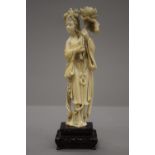 A 19th century Chinese carved ivory figure of Guanyin, mounted on a pierced wooden stand. 23.