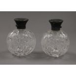 A pair of silver topped cut glass scent bottles. 10 cm high.