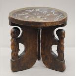 An African wooden stool inlaid with trade beads and copper supported on three figural legs.