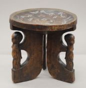 An African wooden stool inlaid with trade beads and copper supported on three figural legs.