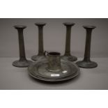 A set of four pewter candlesticks, three pewter plates and a small tankard.