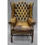 A mahogany framed leather wing back arm chair. 79 cm wide.