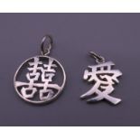 Two Chinese white metal pendants. The largest 2 cm high.