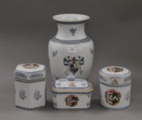A porcelain vase decorated with a heraldic crest and three similar lidded pots.