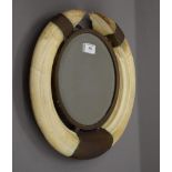 A Victorian mirror mounted with boar's tusks. 39 cm wide, 35.5 cm high, 4 cm deep.