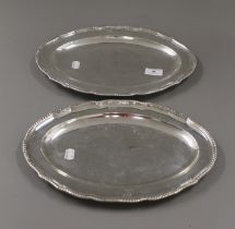 A pair of George III silver serving platters, each engraved with a crest, hallmarked London 1773.