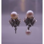 A pair of 14 ct white gold diamond and pearl earrings. One lacking drop. 2 cm high. 8.