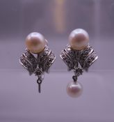 A pair of 14 ct white gold diamond and pearl earrings. One lacking drop. 2 cm high. 8.