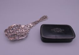 A pierced silver spoon and a papier mache snuff box. The former 12 cm long.