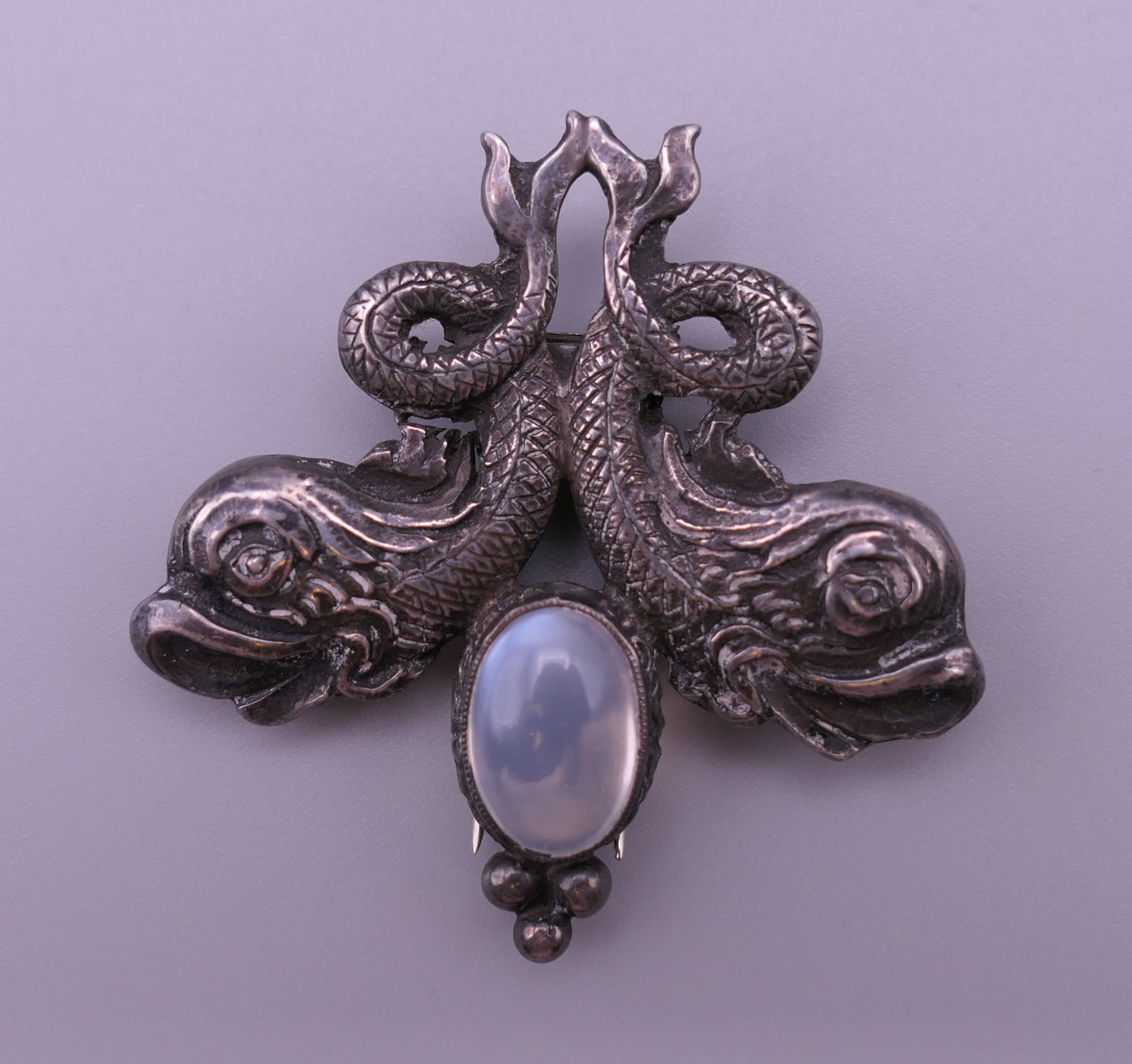 A silver and moonstone dolphin brooch. 4 cm wide.