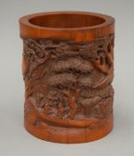 A Chinese bamboo brush pot carved with figures in a landscape and lines of calligraphy. 17 cm high.