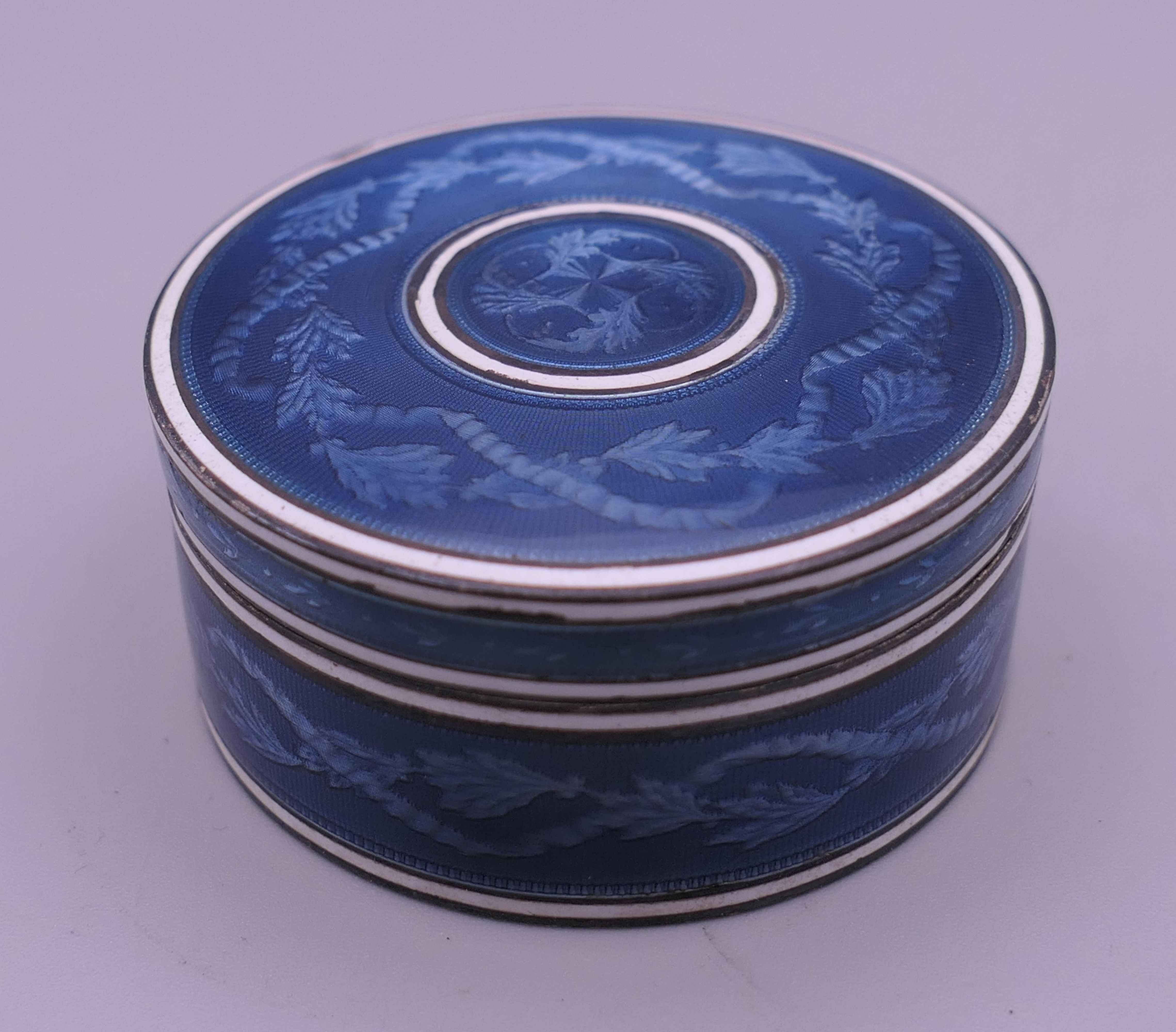 A Continental blue enamel decorated silver box. 4.5 cm diameter.