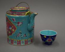 A Chinese Peranakan Nyonya ware teapot and tea bowl in basket. 28 cm wide overall.