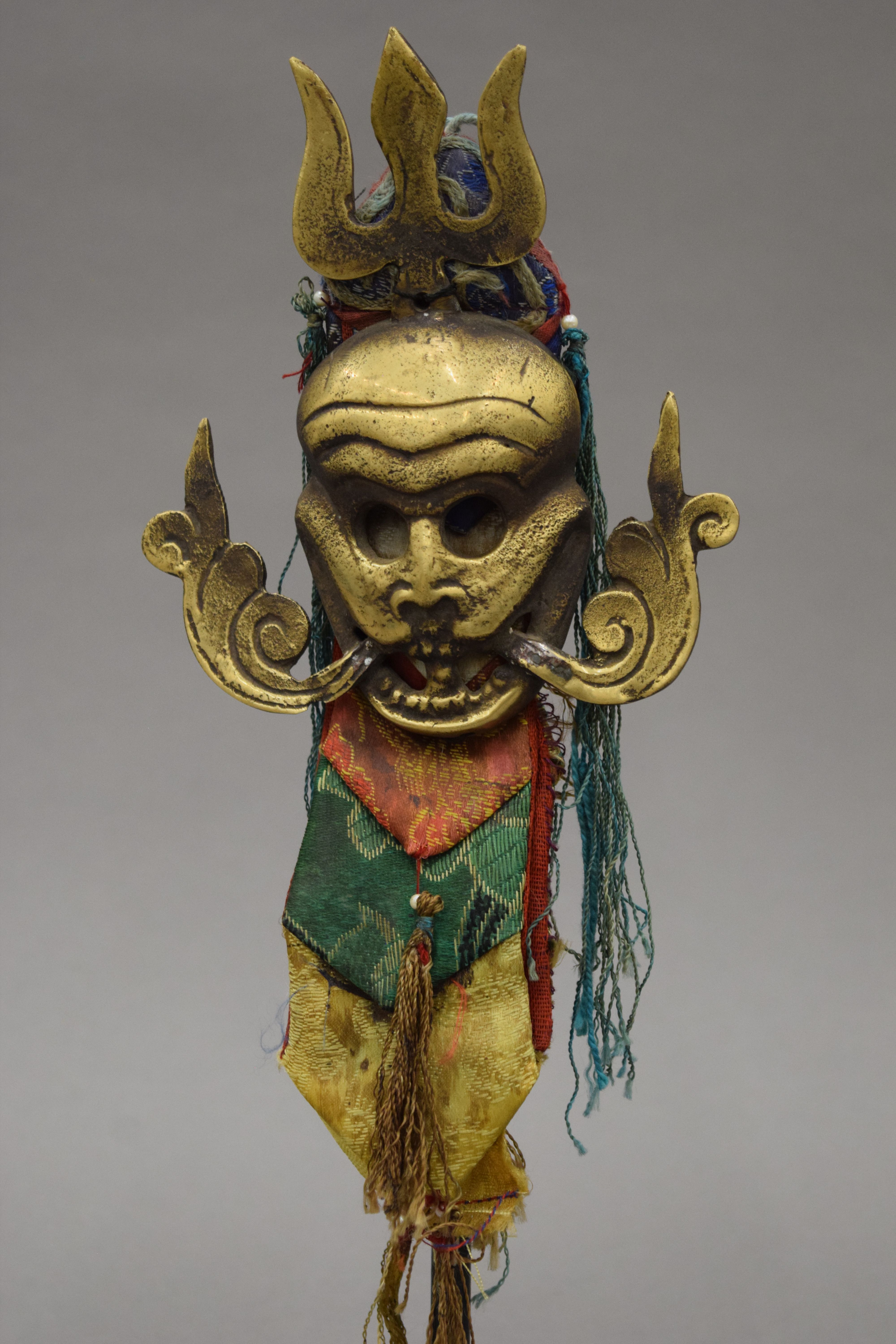 A 19th century Eastern bronze mask with textiles mounts, mounted on a display stand. 28. - Image 2 of 3