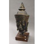 A large Buddha's head mounted on a wooden plinth base. 69 cm high.