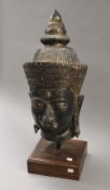 A large Buddha's head mounted on a wooden plinth base. 69 cm high.