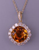 An 18 ct gold citrine and diamond pendant on an 18 ct gold chain. Approximately 0.