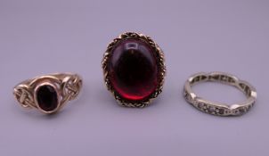 A 9 ct gold and garnet ring, an unmarked gold ring and a 9 ct white gold eternity ring. 9.