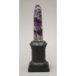 A mineral specimen obelisk mounted on a display stand. 21 cm high overall.