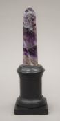 A mineral specimen obelisk mounted on a display stand. 21 cm high overall.