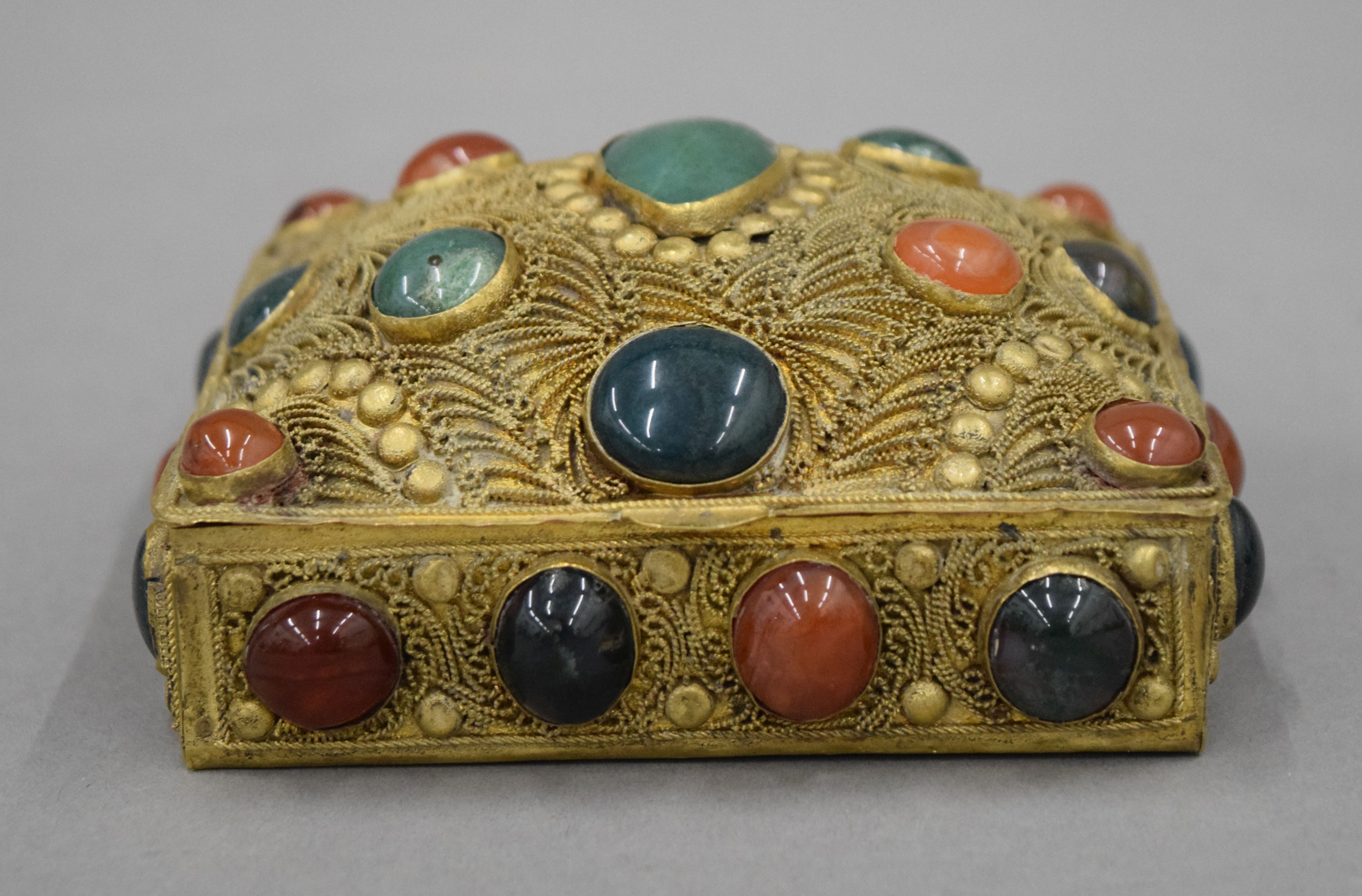An Indian gilt box set with cabochon stones. 11 cm wide.