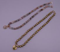 Two bead necklaces, each set with a 9 ct gold mounted pendant.