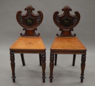 A pair of early 19th century mahogany hall chairs each painted with a greyhound crest. 39.5 cm wide.