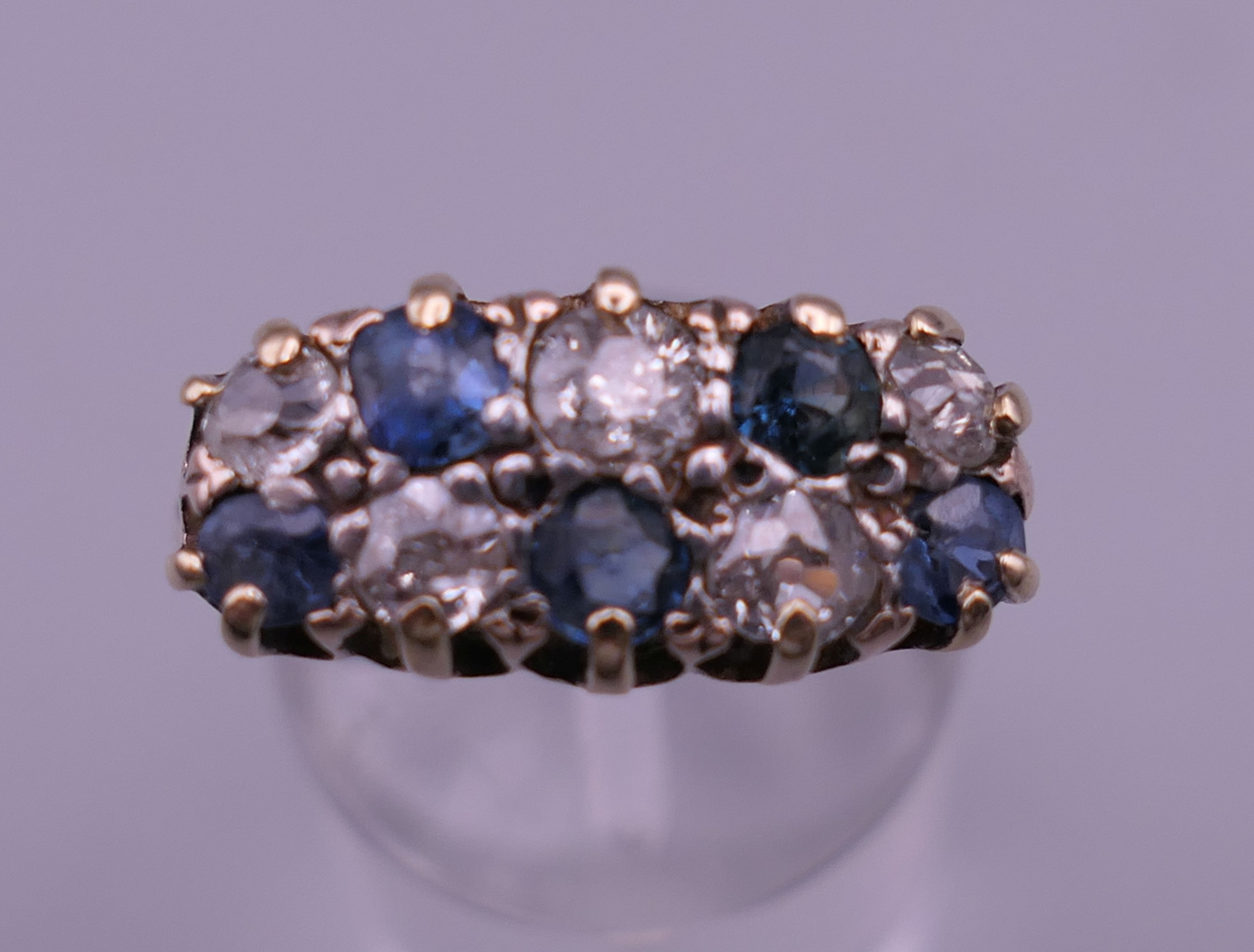 An 18 ct gold diamond and sapphire ring. 8 mm high, 17 mm wide. Ring size Q/R.