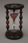 A sand timer in a turned and painted wooden frame. 20 cm high.