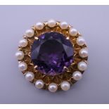A 9 ct gold amethyst and seed pearl brooch. 3 cm diameter. 10.4 grammes total weight.